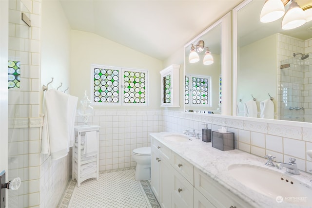 bathroom with lofted ceiling, tile patterned flooring, tile walls, vanity, and toilet