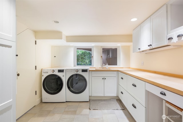 laundry area featuring separate washer and dryer, sink, and cabinets