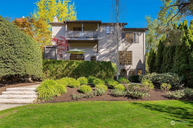 view of front of house featuring a balcony and a front yard