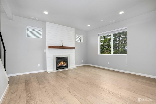 unfurnished living room with a fireplace and light hardwood / wood-style floors