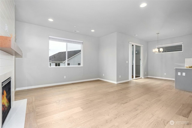 unfurnished living room with light hardwood / wood-style floors and a notable chandelier