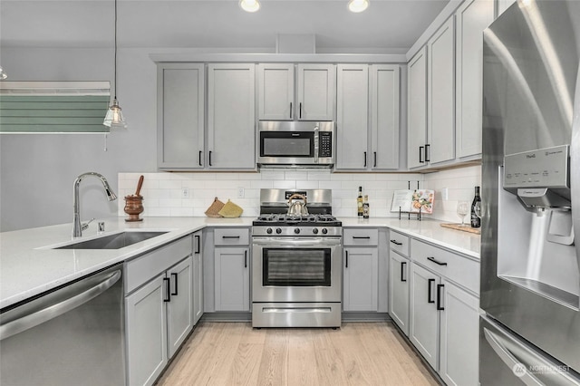 kitchen with decorative backsplash, sink, decorative light fixtures, stainless steel appliances, and gray cabinets