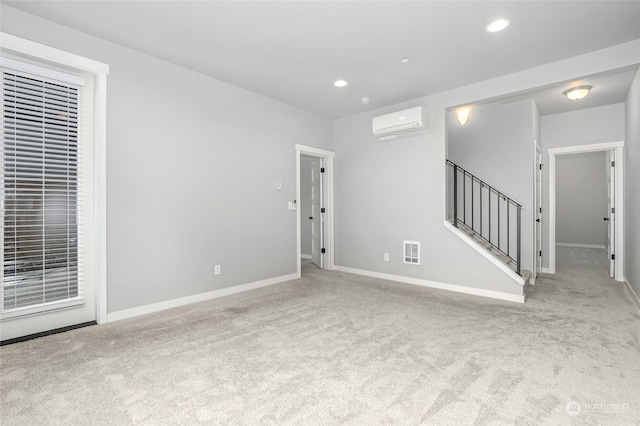 unfurnished room with an AC wall unit and light colored carpet