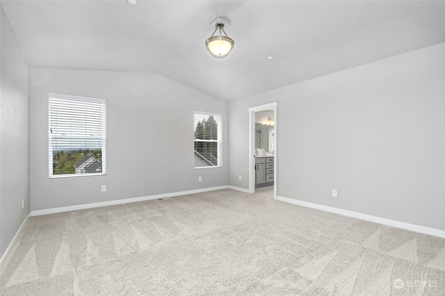 carpeted spare room featuring lofted ceiling