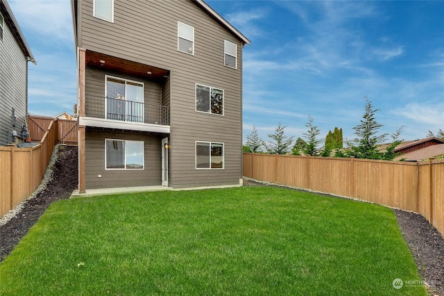 back of house with a balcony and a lawn