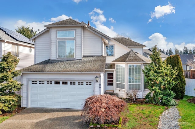 traditional-style house with driveway, an attached garage, and a shingled roof