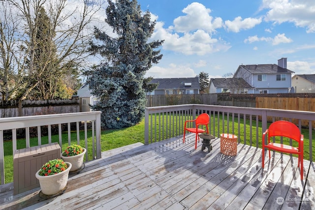 deck featuring a fenced backyard, a residential view, and a lawn