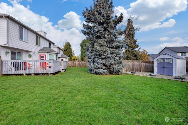 view of yard with a shed, an outdoor structure, a fenced backyard, and a wooden deck