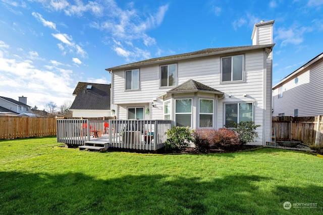 back of property featuring a deck, a fenced backyard, a yard, and a chimney