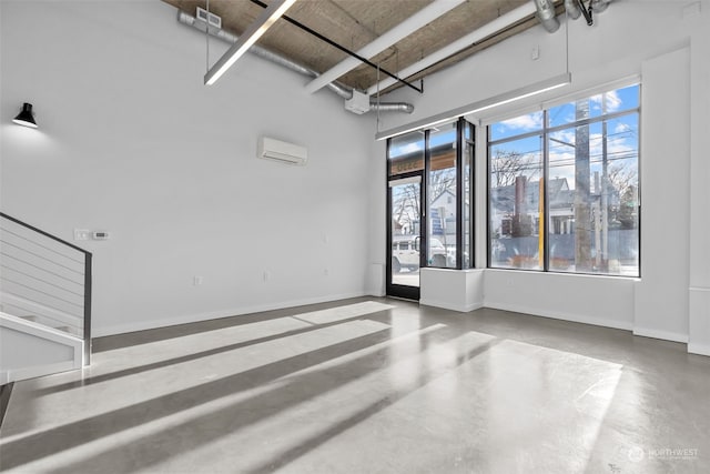 unfurnished room with concrete flooring, a high ceiling, and a wall unit AC