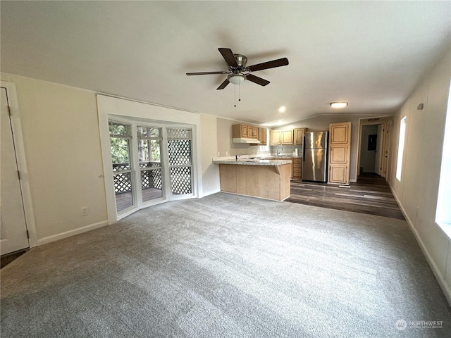 unfurnished living room with ceiling fan, vaulted ceiling, and dark carpet