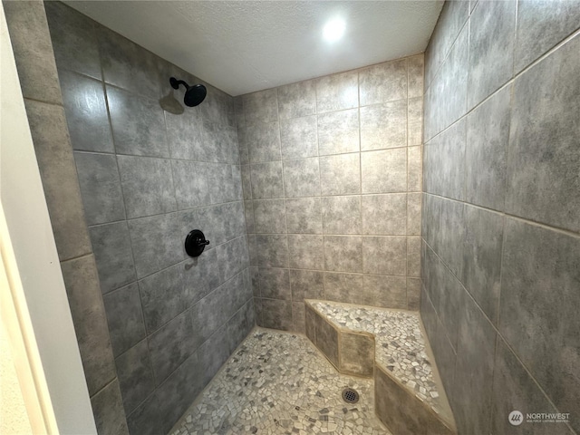 bathroom with tiled shower and a textured ceiling