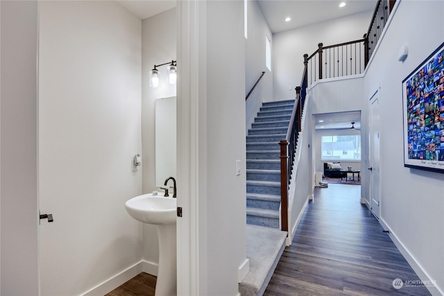 stairs featuring hardwood / wood-style flooring, ceiling fan, and a towering ceiling