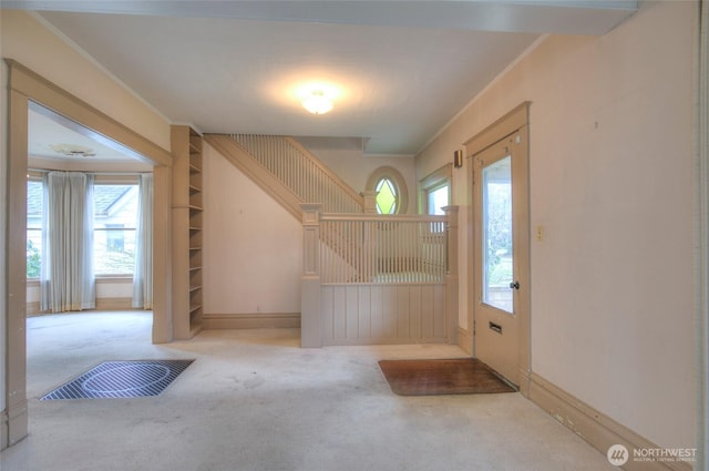 foyer entrance with baseboards, carpet, and ornamental molding