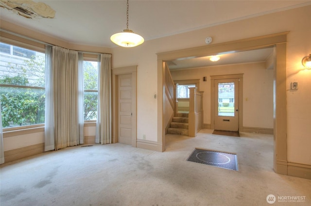 entrance foyer featuring baseboards, carpet, stairs, and crown molding