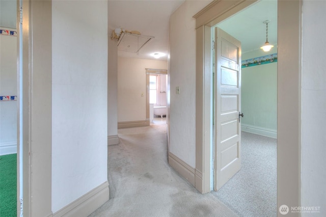 hall featuring attic access, baseboards, and carpet