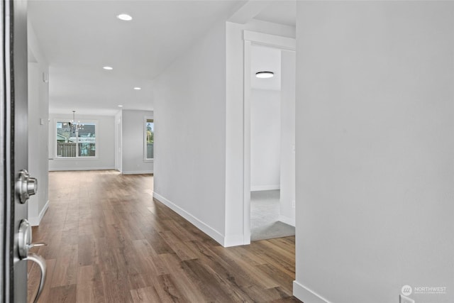 hallway with dark hardwood / wood-style flooring and an inviting chandelier