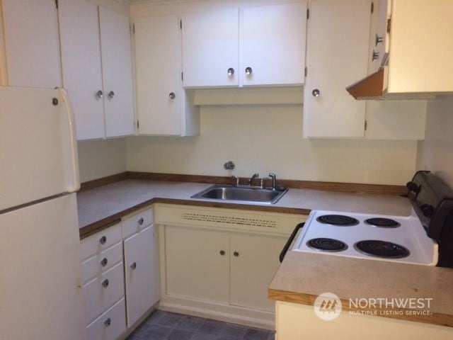 kitchen with sink, white appliances, and white cabinetry