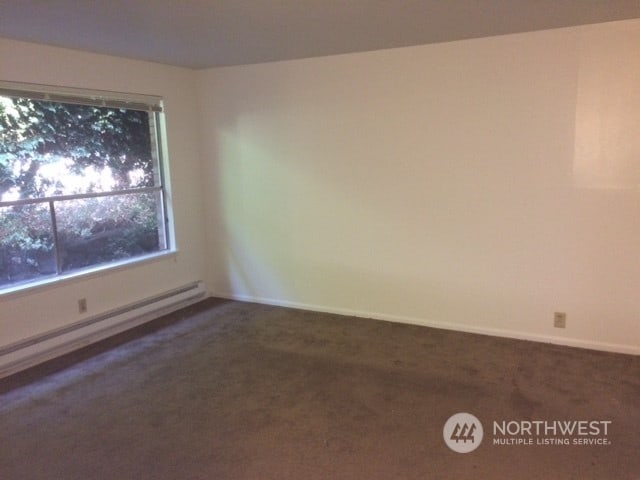 carpeted empty room featuring a baseboard radiator