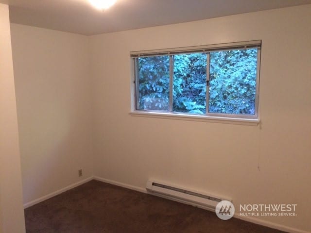 carpeted spare room featuring baseboard heating