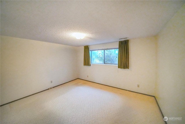 carpeted spare room featuring a textured ceiling