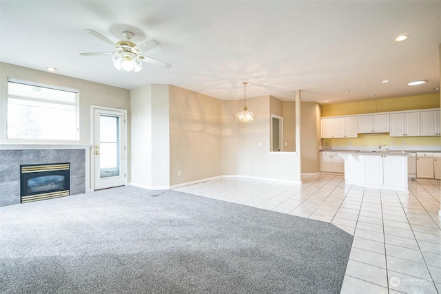 unfurnished living room with light tile patterned floors, ceiling fan with notable chandelier, and a fireplace