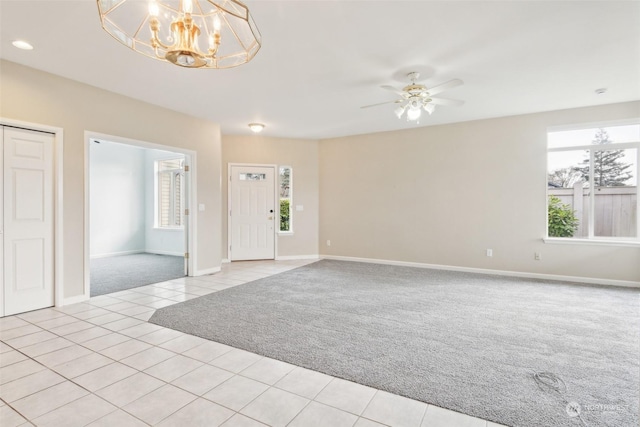 carpeted spare room with ceiling fan with notable chandelier