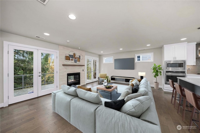 living room with french doors, a premium fireplace, and dark hardwood / wood-style floors