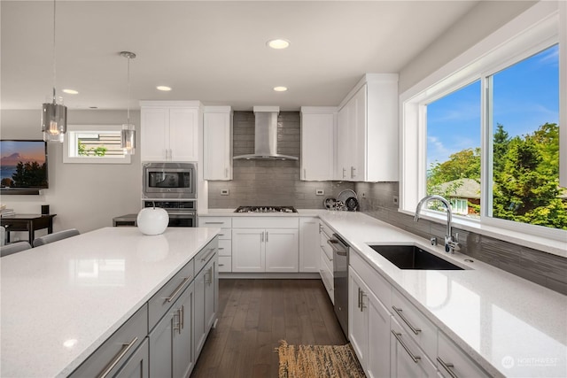 kitchen featuring white cabinetry, sink, stainless steel appliances, and wall chimney range hood