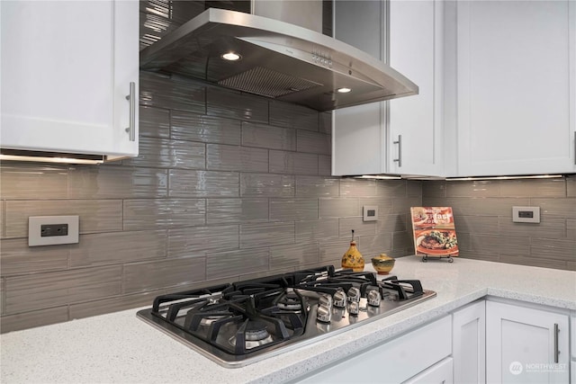 kitchen featuring tasteful backsplash, stainless steel gas stovetop, range hood, and white cabinetry