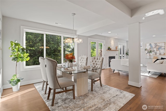 dining room with a fireplace, baseboards, an inviting chandelier, and hardwood / wood-style floors