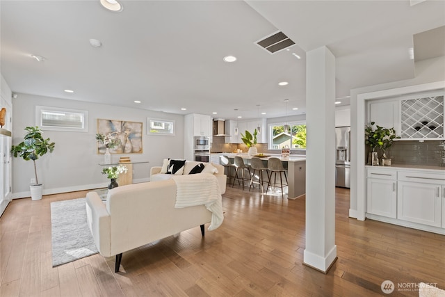 living area with recessed lighting, baseboards, visible vents, and wood finished floors