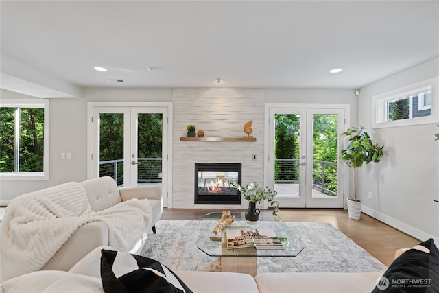 living area featuring a multi sided fireplace, french doors, wood finished floors, baseboards, and recessed lighting