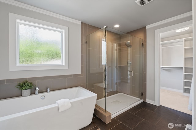 bathroom featuring tile patterned floors, visible vents, ornamental molding, a soaking tub, and a stall shower