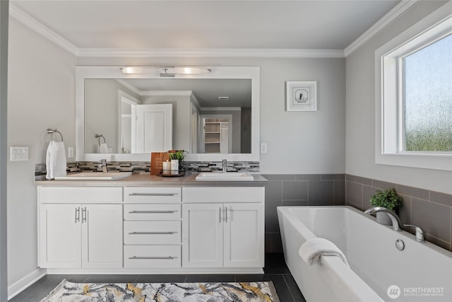 full bathroom featuring a sink, ornamental molding, double vanity, and a freestanding bath