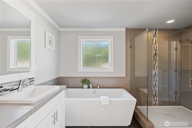 bathroom featuring vanity, a freestanding tub, tile walls, a shower stall, and ornamental molding