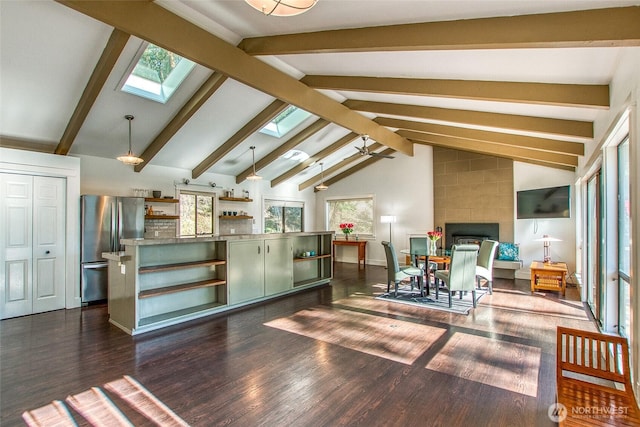 interior space with dark wood-type flooring, vaulted ceiling with skylight, a fireplace, and baseboards