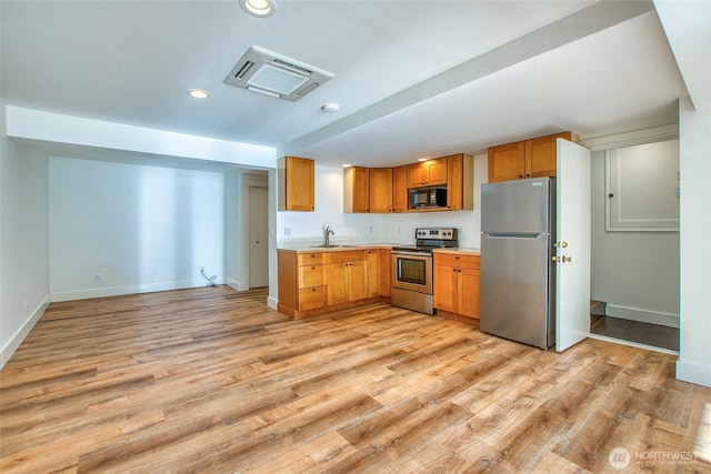 kitchen with baseboards, recessed lighting, stainless steel appliances, light countertops, and light wood-style floors