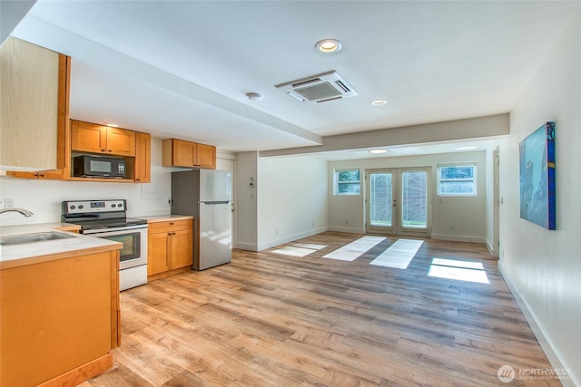 kitchen with light wood finished floors, light countertops, french doors, stainless steel appliances, and a sink