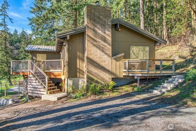 view of front of property featuring stairway, a deck, a chimney, and fence