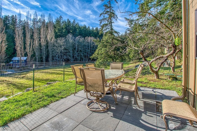 view of patio / terrace featuring a wooded view, outdoor dining area, and a fenced backyard