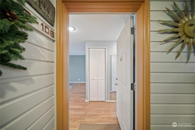 corridor with light hardwood / wood-style floors and a textured ceiling