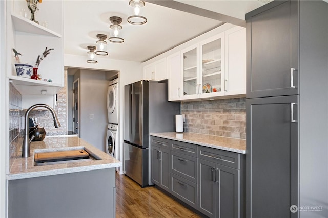 kitchen with stacked washer and dryer, white cabinets, sink, backsplash, and gray cabinets