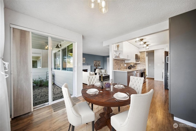 dining space with sink, dark wood-type flooring, and a textured ceiling