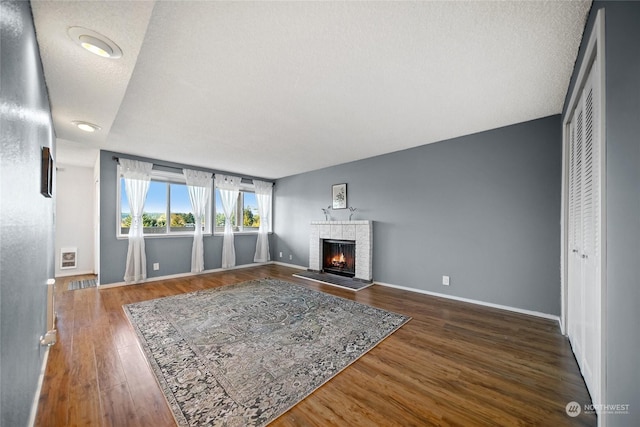 living room featuring dark wood-type flooring, a textured ceiling, and a fireplace