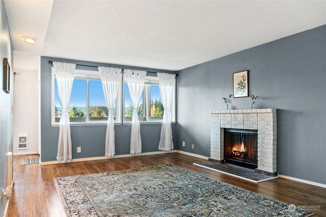 unfurnished living room featuring hardwood / wood-style flooring, a brick fireplace, and heating unit