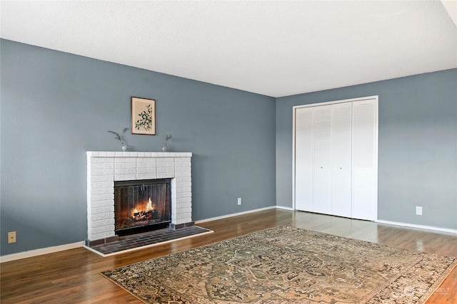 unfurnished living room with a brick fireplace and hardwood / wood-style floors