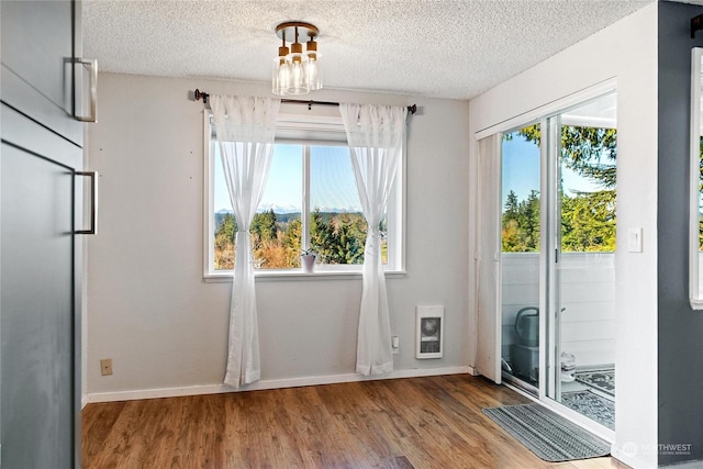 interior space featuring hardwood / wood-style floors, a textured ceiling, and heating unit