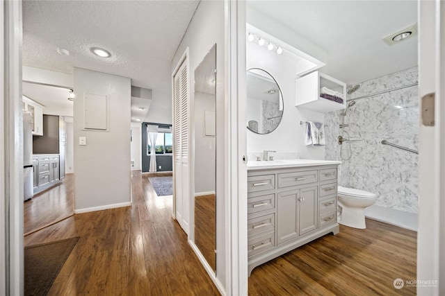 bathroom with hardwood / wood-style floors, toilet, a textured ceiling, walk in shower, and vanity