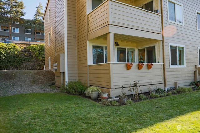 view of home's exterior with a balcony and a lawn